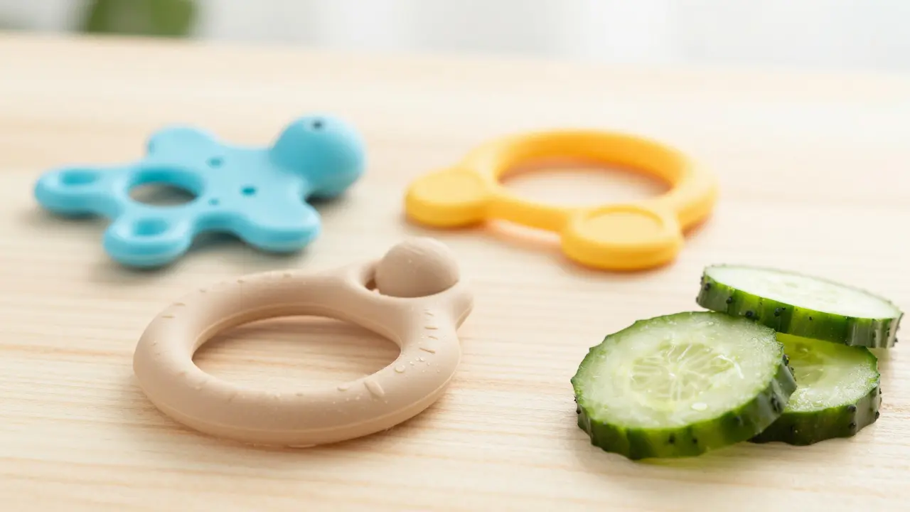 Sada pomůcek pro úlevu při prořezávání zubů, včetně kousátka a chlazeného okurce.